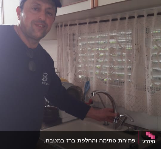 אדם ליד כיור מטבח עם ברז חדש